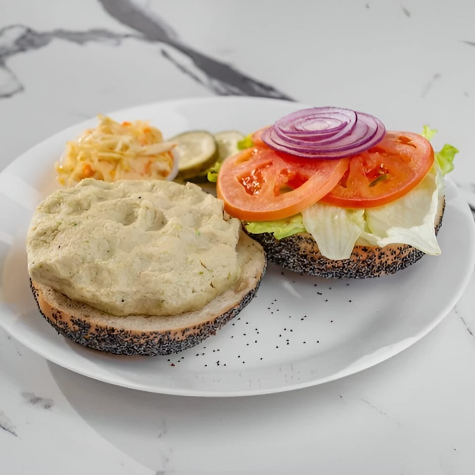 Delicious Bagels' poppy seed bagel with cream cheese, lettuce, tomato, red onion, and a side of pickles and coleslaw.